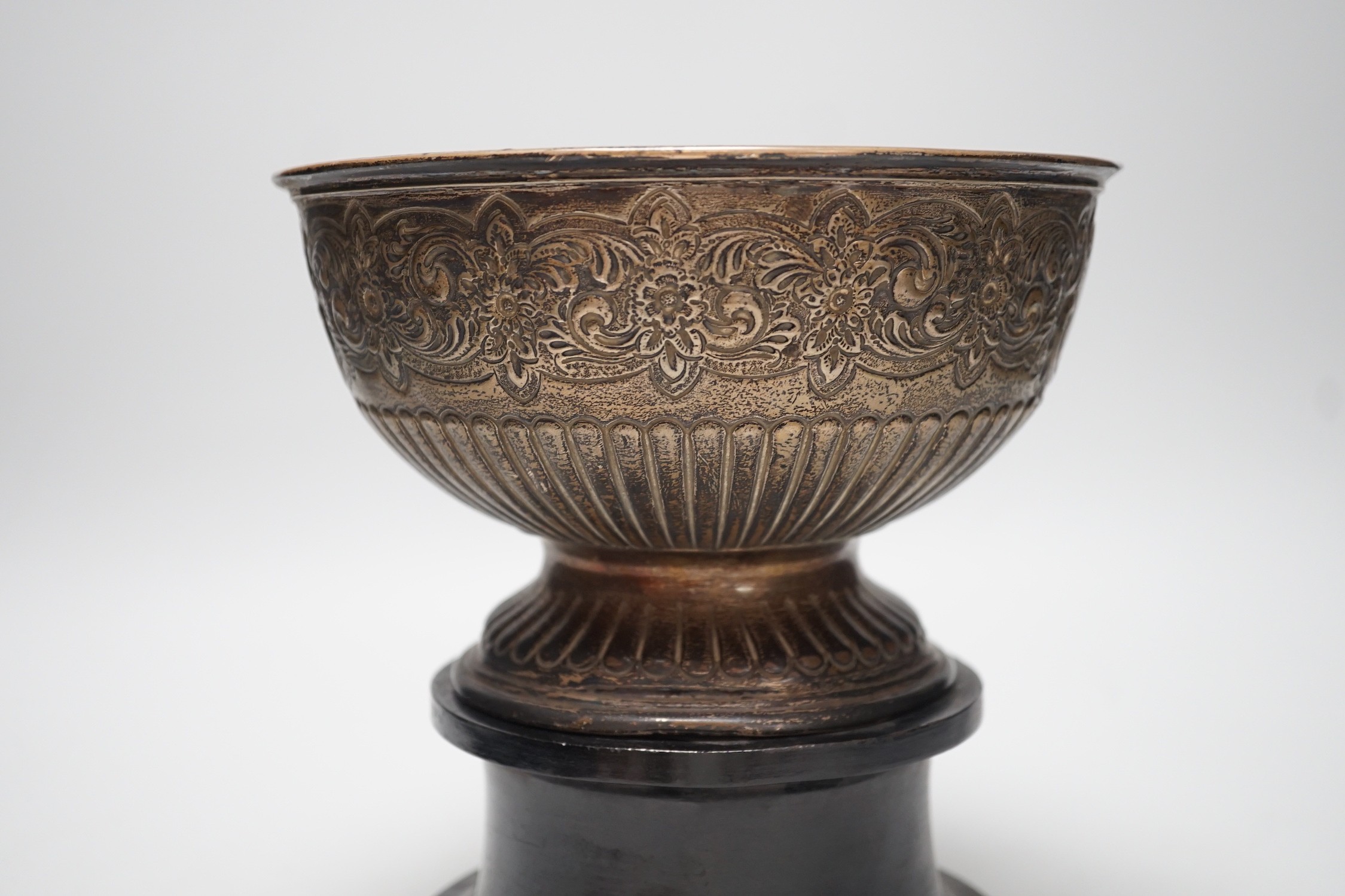 A late Victorian demi fluted and embossed silver presentation rose bowl, with engraved inscription, James Deakin & Sons, Sheffield, 1896, diameter 19.5cm, 12.2oz, on ebonised plinth